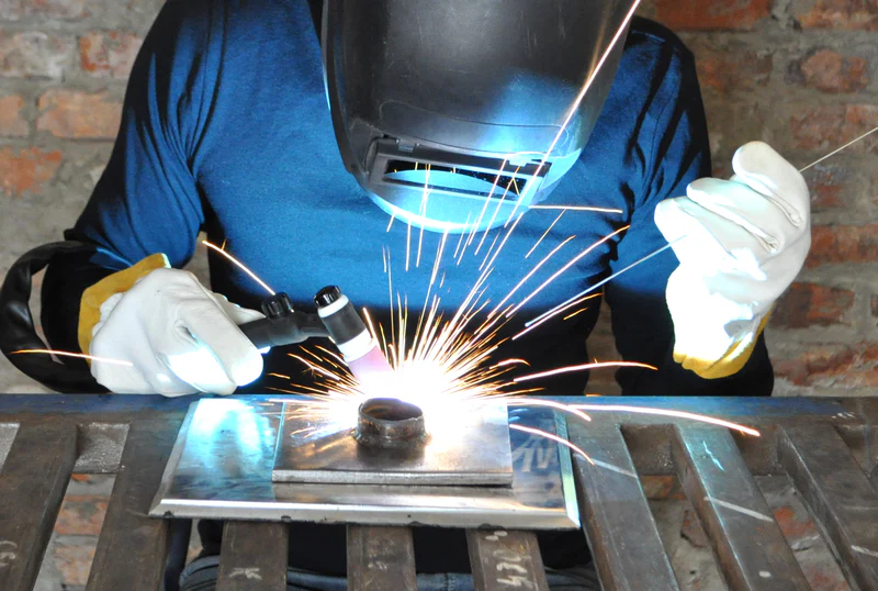 Welders wearing welding gloves working diligently